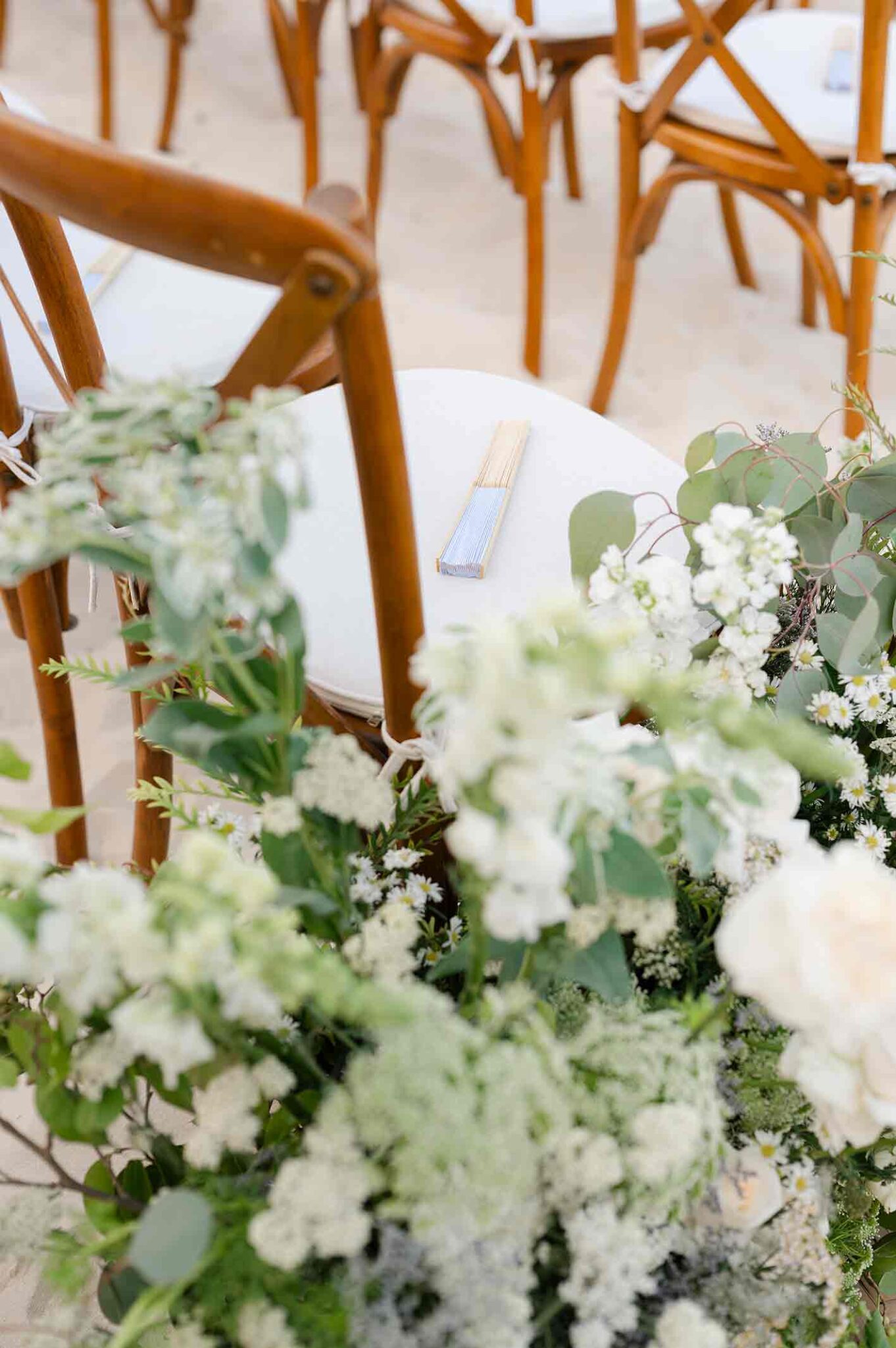 Elegant wedding aisle decor with white flowers and greenery at beach destination wedding