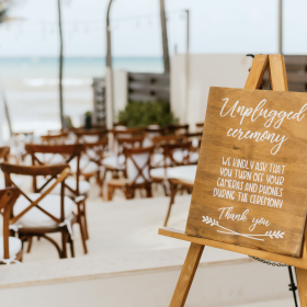 A wedding sign for an unplugged ceremony displayed at a beach venue